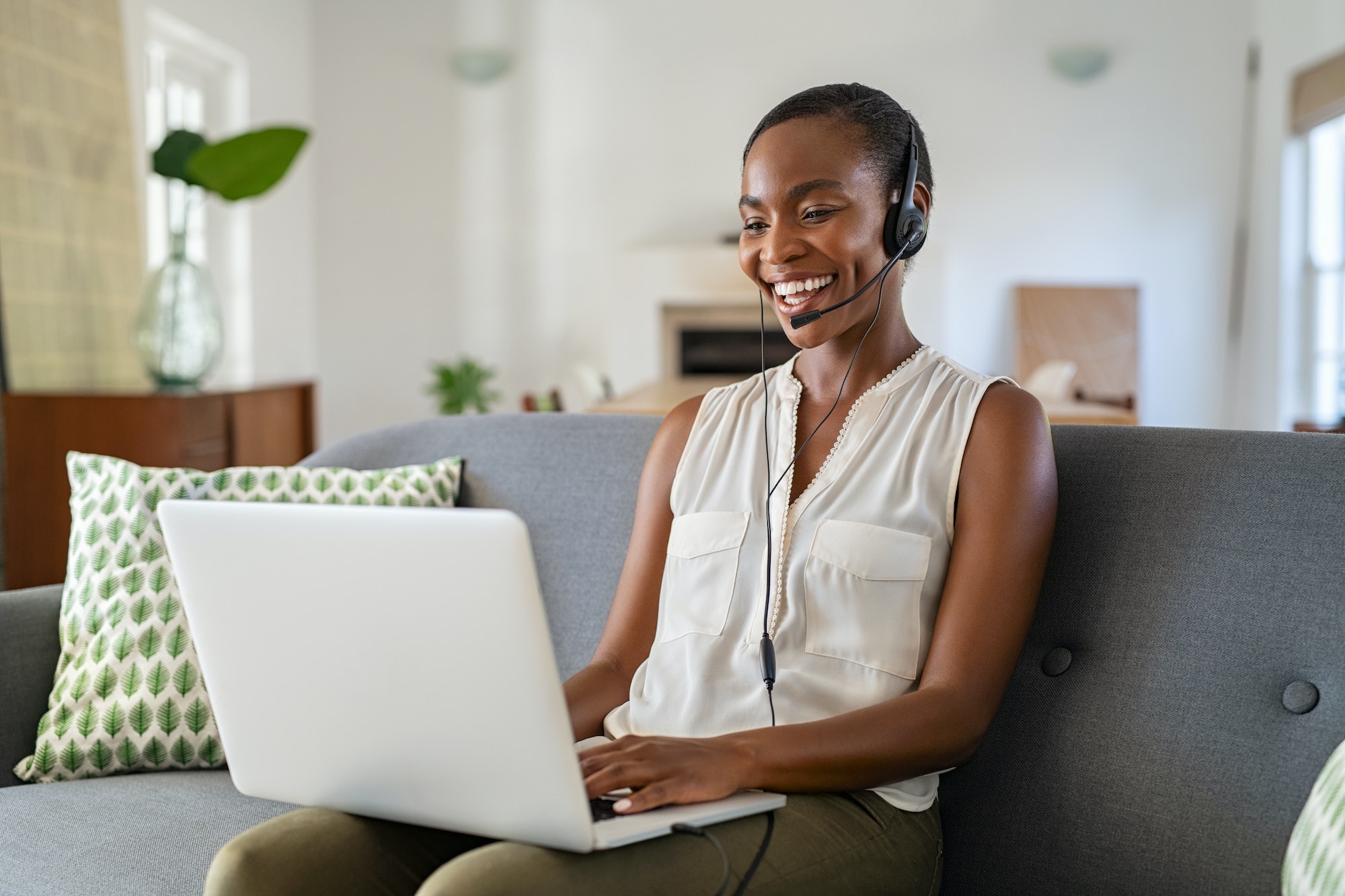 Mature black woman using laptop for video call while working from home